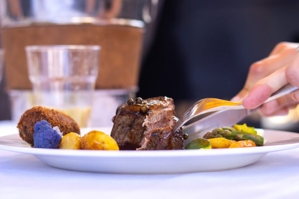 Een close-up van een steak die gesneden wordt tijdens een rondvaart met diner Amsterdam.