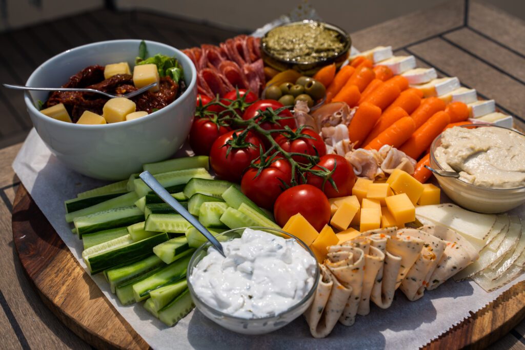 Een plank met verschillende snacks (groenten, dips, kaas en vlees).