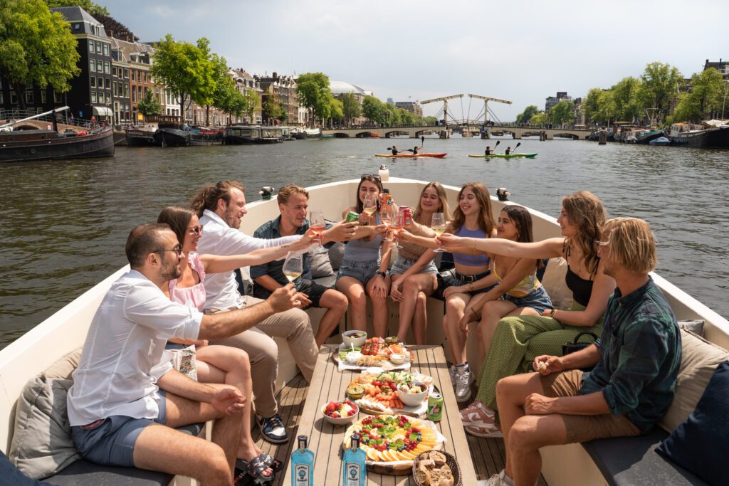Groep mensen die hun glas opheffen tijdens een Amsterdamse tapas rondvaart.