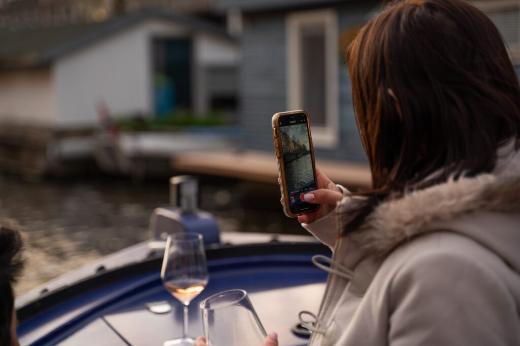 Vrouw die de grachten filmt van op een rondvaart met eten Amsterdam