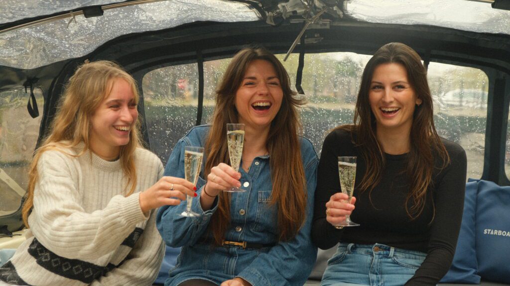 3 meisjes met een glas cava in hun handen op de beste rondvaart Amsterdam