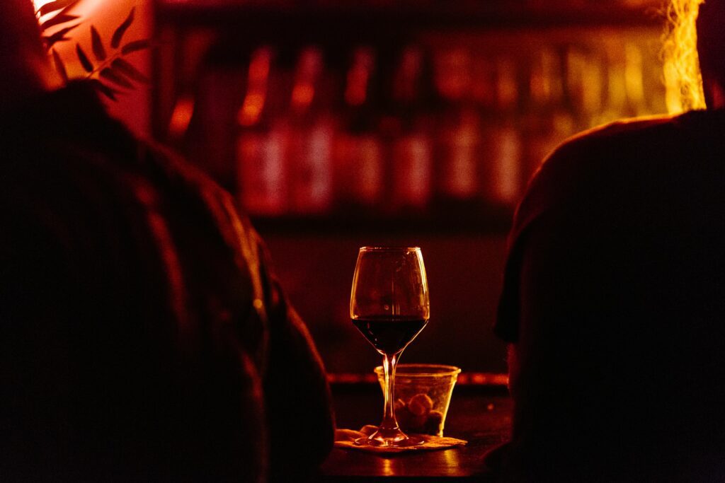 A silhouette of two people's shoulders with a glass of wine in the middle.