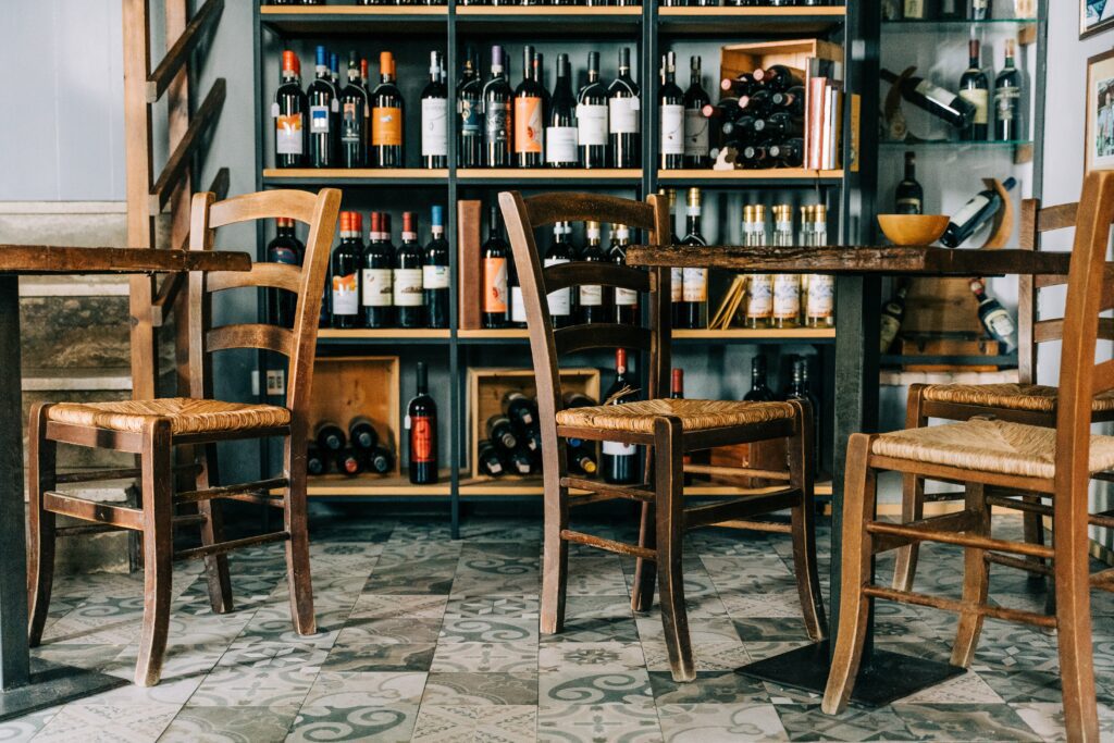 Chairs and tables with bottles of wine in the background in a wine bar Amsterdam