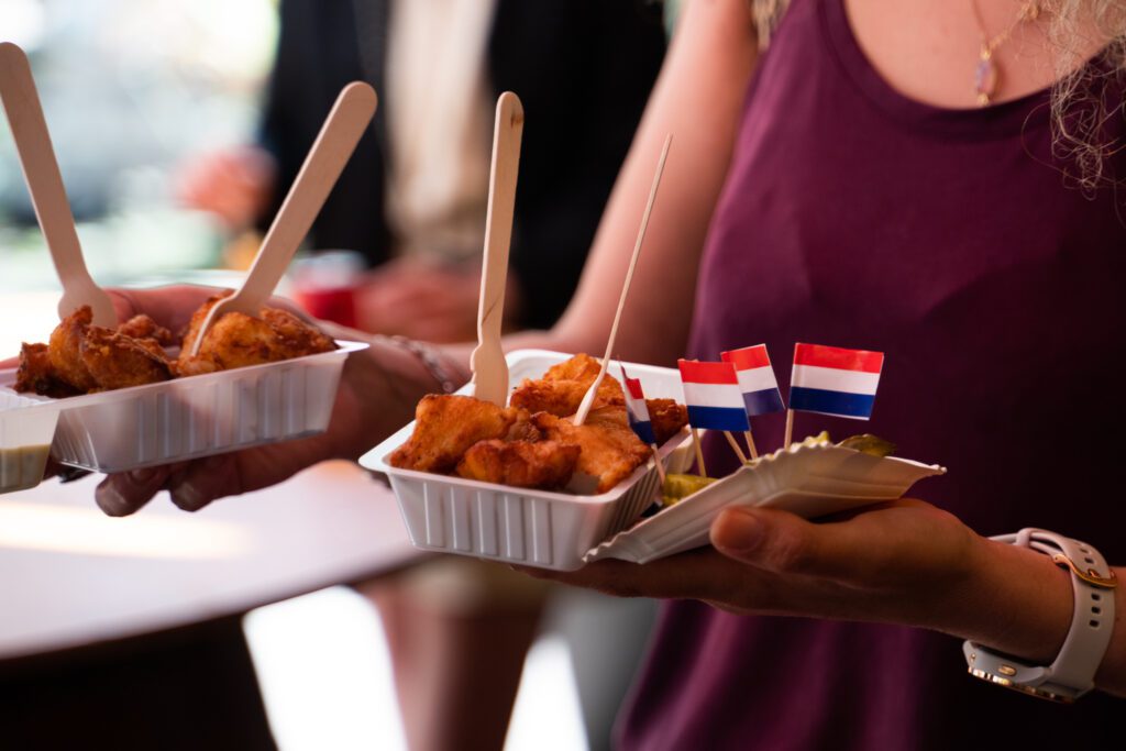 Person holding traditional Dutch street food dishes. 