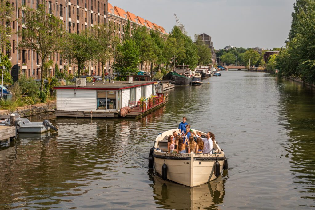 People cheering with their glass on a boat on the Amsterdam canals. 