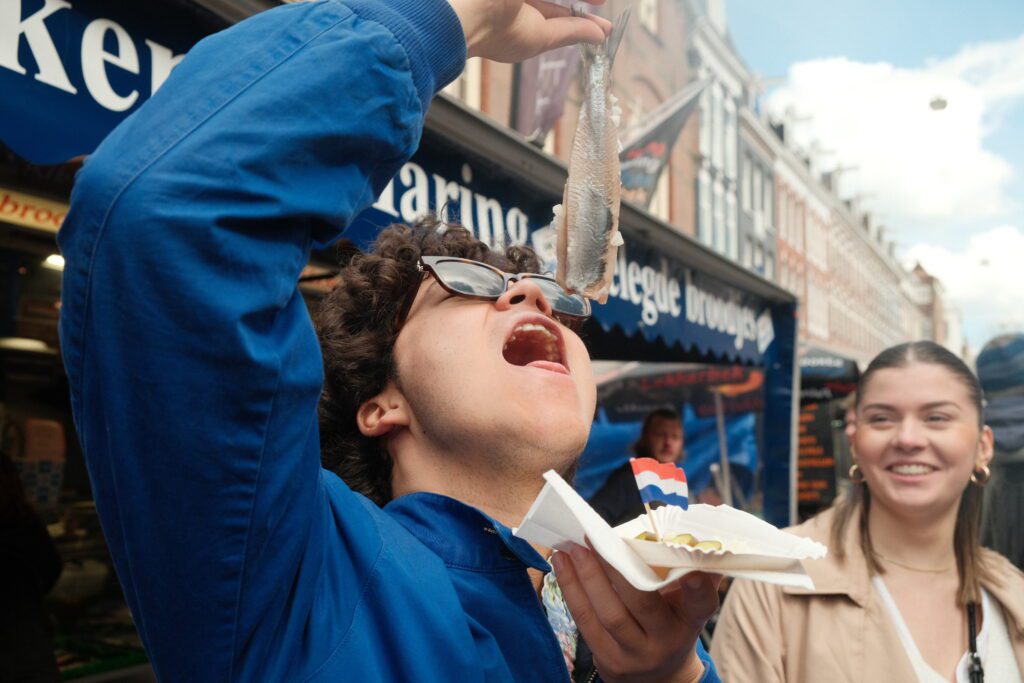 A person eating herring street food amsterdam