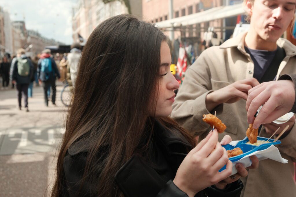 Person enjoying Kibbeling on a street food Amsterdam market