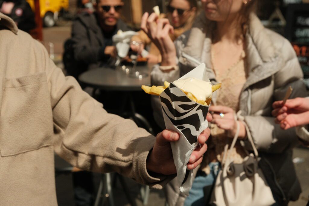 Person holding a cone with fries and mayonaise. 