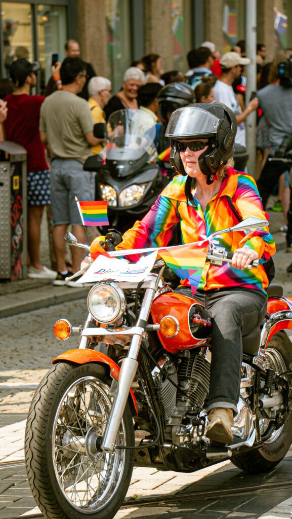 A person sitting on a scooter dressed in rainbow colours